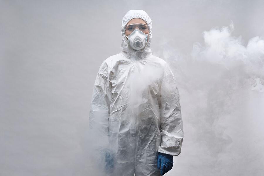 A person in a white protective suit and half-face respirator, seen from the side